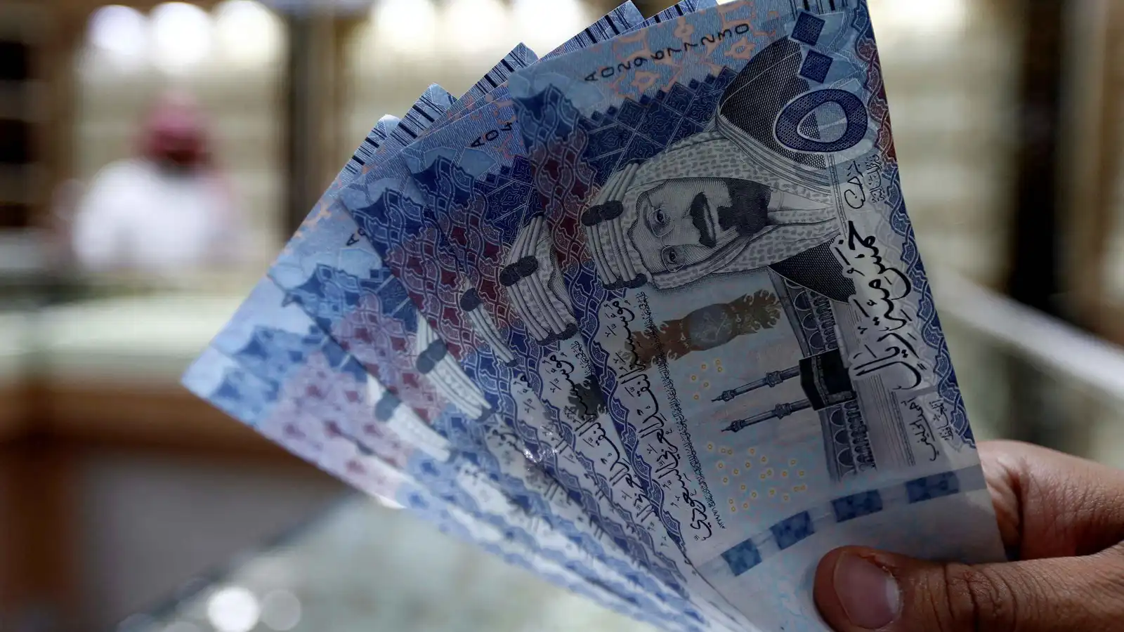 صراف سعودي يعرض أوراقاً نقدية من الريال السعودي في محل صرافة بالرياض، السعودية، يوم 27 يوليو 2017. 