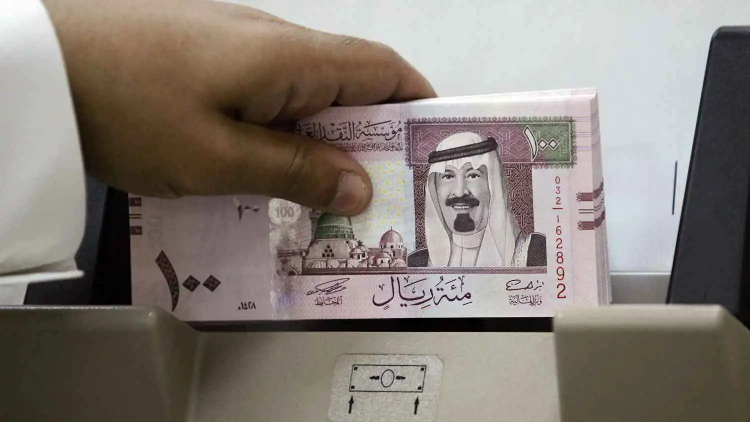 مصرفي سعودي يعدّ أوراقاً نقدية جديدة من فئة 100 ريال في أحد بنوك الرياض، 5 يونيو 2007