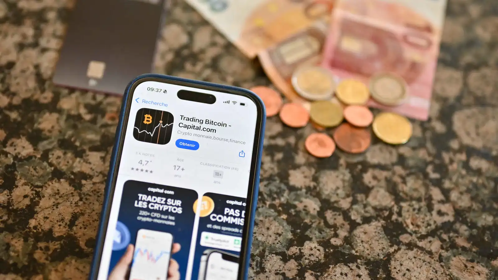 شاشة هاتف محمول يحتوي على تطبيق تداول «بيتكوين»، وفي الخلفية بطاقة ائتمان ونقد، مدينة فرساي، فرنسا، 19 أغسطس 2025.
