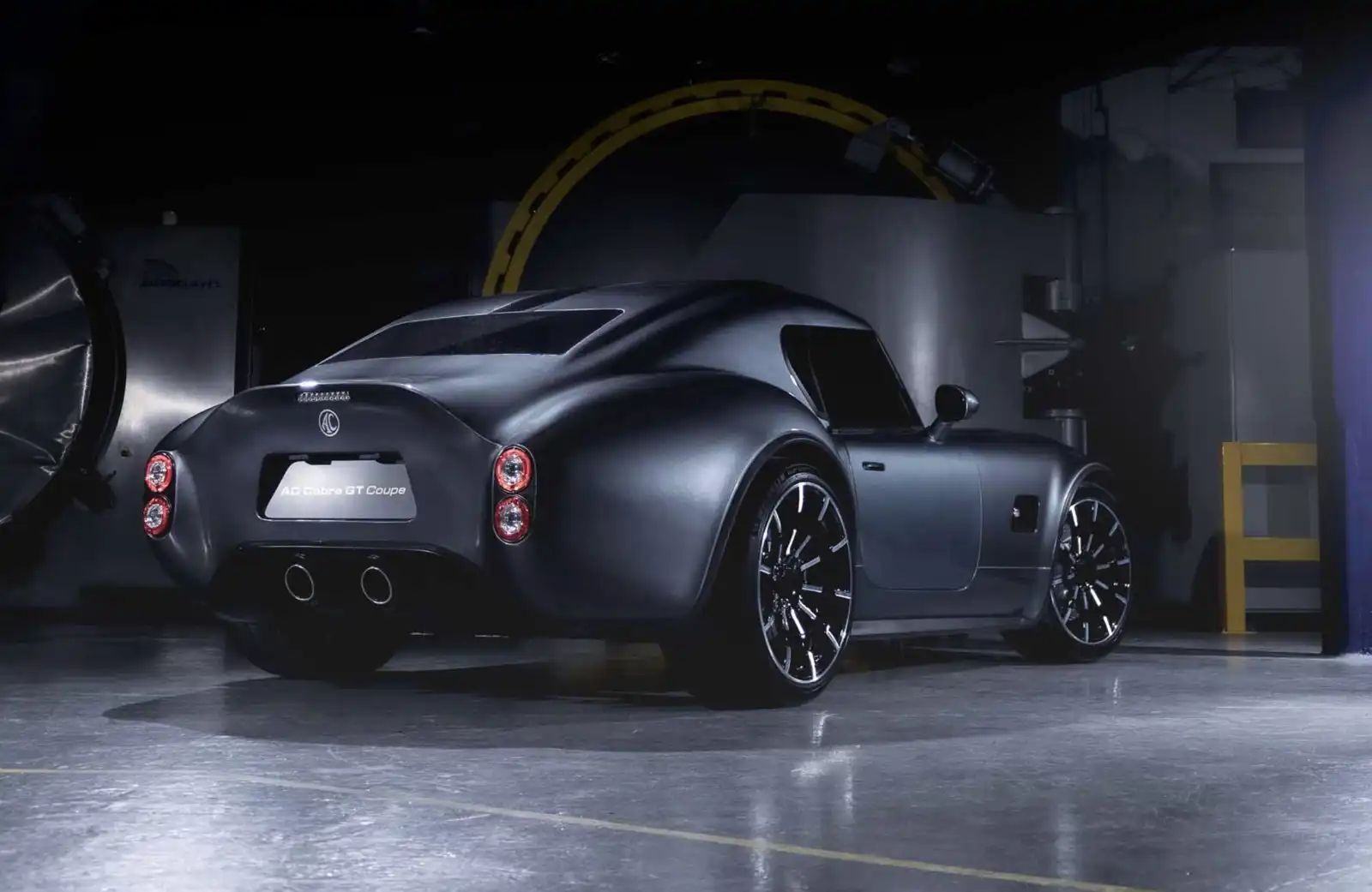 المؤخرة العضلية لـ AC Cobra GT Coupe مع مصابيح دائرية وعادم مزدوج يعكس الطابع الرياضي.