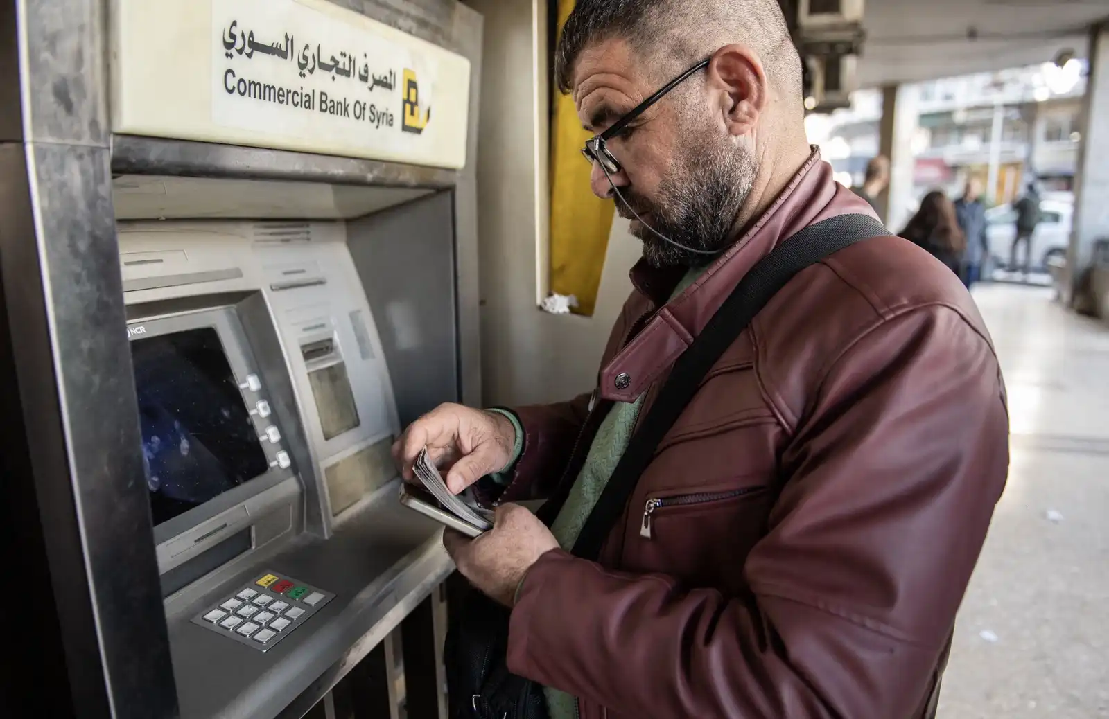 سوري يسحب أوراق نقدية سورية قديمة تزامناً مع إطلاق مصرف سوريا المركزي الانتقال إلى عملة جديدة، في دمشق، سوريا -28 ديسمبر 2025.