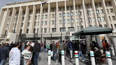 يصطفون خارج المقر الرئيس للبنك المركزي السوري في العاصمة دمشق يوم 30 ديسمبر 2024.