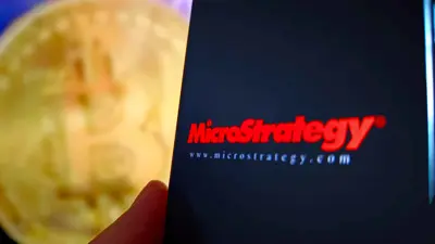 شعار شركة «مايكروستراتيجي» يظهر في المقدمة بينما تتصدر خلفيته عملة «بيتكوين» يوم 19 فبراير 2025