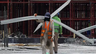 عاملان في موقع بناء مشروع بالعاصمة السعودية الرياض يوم 16 يونيو 2022.