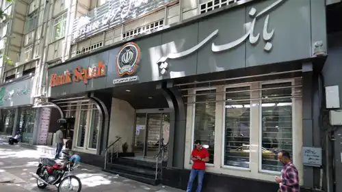 يقف أمام فرع لبنك «بنك سبه» في العاصمة الإيرانية طهران، يوم 15 يونيو 2022.