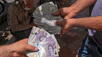 يعرضان أوراق الجنيه الإسترليني والدولار الأميركي خارج محل صرف عملات في العاصمة الإيرانية طهران يوم 15 يونيو 2021