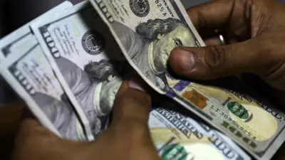 يعدّ أوراق الدولار الأميركي داخل محل صرافة في العاصمة البنغالية دكا يوم 19 مايو 2022