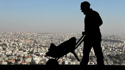 عامل بناء يدفع عربة يدوية في موقع مشروع «بوابة الأردن» السكني في عمان، 2 نوفمبر 2010.