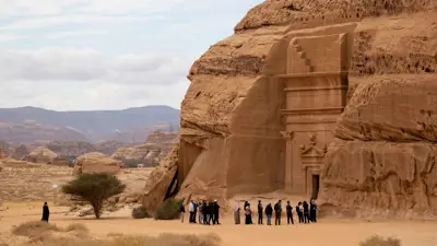 مجموعة من السياح عند موقع الحِجر الأثري، في محافظة العُلا شمال غربي السعودية، يوم 31 يناير 2022. يُعدّ الحِجر أول موقع في المملكة يُدرج ضمن قائمة اليونسكو للتراث العالمي