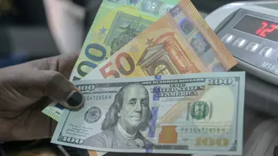 موظفة في أحد محال الصرافة في العاصمة الكينية، نيروبي، تعرض أوراقاً نقدية من الدولار الأميركي واليورو.
