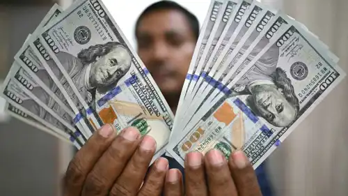 شخص يعرض أوراقاً نقدية من الدولار الأميركي في محل صرافة في العاصمة الهندية نيودلهي، يوم 31 يوليو 2025.
