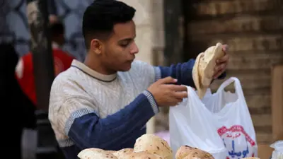  شاب يشتري الخبز في سوق شعبي بالقاهرة
