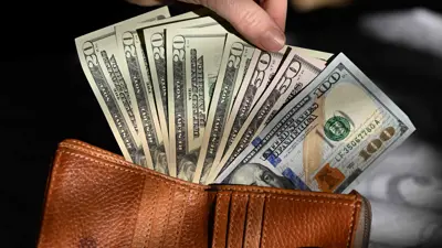 يحمل أوراقاً نقدية من الدولار الأميركي ضمن صورة توضيحية ملتقطة في مدينة إدمونتون بمقاطعة ألبرتا الكندية يوم 4 فبراير 2025. 