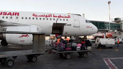 عامل ينقل أمتعة بجوار طائرة تابعة للخطوط الجوية التونسية، في مطار قرطاج الدولي في تونس، يوم 19 يوليو 2016.