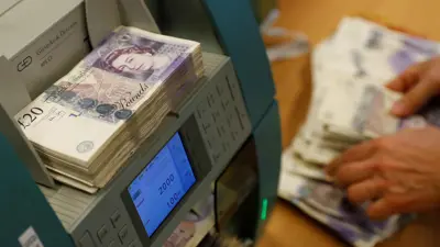 أوراق نقدية من الجنيه الإسترليني في آلة عد نقود.