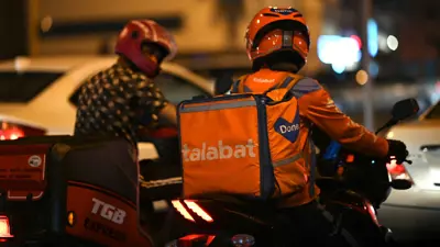 سائق من خدمة توصيل الطعام عبر الإنترنت "طلبات" ينتظر عند إشارة مرور في الدوحة يوم 27 أكتوبر 2022
