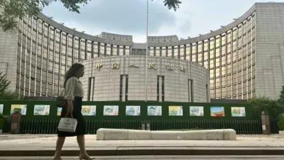 تسير بجوار مبنى بنك الشعب الصيني في العاصمة بكين يوم 1 يوليو 2024