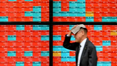 يمر أمام لوحة إلكترونية تعرض أسعار أسهم مؤشر «نيكاي 225» في البورصة في العاصمة اليابانية طوكيو، يوم 12 أبريل 2024.