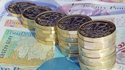 عملات معدنية جديدة من فئة جنيه إسترليني مرتبة بارتفاعات متزايدة على أوراق نقدية بريطانية.