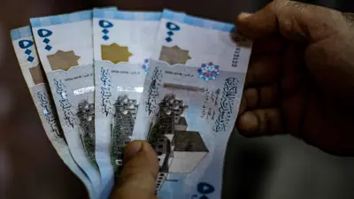 شخص يحمل عملات ورقية من الليرة السورية في إحدى أسواق مدينة القامشلي السورية يوم 10 سبتمبر 2019.