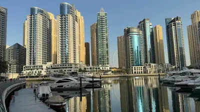 صورة أبراج سكنية وفندقية منعكسة على مياه القناة الرئيسية في منطقة "دبي مارينا" في دبي، يوم 8 مايو 2024.
