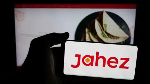 شخص يحمل هاتفاً محمولاً يحمل على شاشته شعار شركة جاهز السعودية لتطبيق توصيل الطعام، 13 يونيو 2025.
