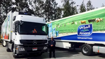 عامل يقف بجوار شاحنتين تحملان إعلانات منتجات شركة «المراعي» في مصنع بمدينة النوبارية، محافظة البحيرة، مصر، يوم 13 مارس 2016.
