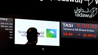 يتابع شاشة تعرض أسهم «أرامكو» داخل السوق المالية السعودية (تداول) في العاصمة الرياض يوم 12 ديسمبر 2019.