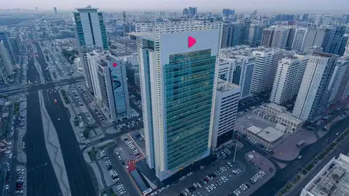 لقطة جوية لمقر بنك أبوظبي التجاري الحديث يتوسط شوارع وأبراج مدينة أبوظبي، الإمارات.