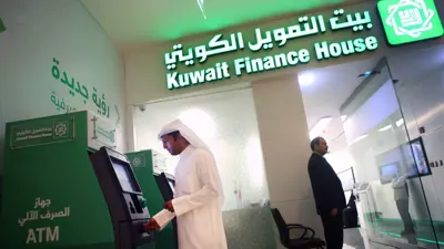 عميل يسحب نقوداً من ماكينة صراف آلي خارج فرع بيت التمويل الكويتي داخل مجمع الأفنيوز، الكويت، يوم 19 نوفمبر 2014.