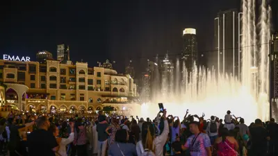 سياح يشاهدون عرضاً مائياً لنافورة دبي في بحيرة برج خليفة في دبي - الإمارات يوم 29 نوفمبر 2023