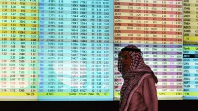 متداول يسير أمام لوحة إلكترونية تعرض حركة الأسهم والمؤشرات في بورصة عمان، الأردن، يوم 21 أكتوبر 2008