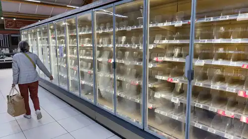 امرأة تسير أمام ثلاجات فارغة مخصصة للأغذية الطازجة في متجر "إنترمارشيه"  ببلدة نيفز غربي فرنسا، بتاريخ 12 أكتوبر 2026، في أعقاب هجوم سيبراني استهدف سلسلتي متاجر فرنسيتين