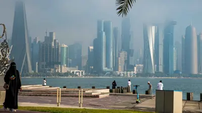 يسيرون على طول كورنيش الدوحة وسط ضباب كثيف يغطي سماء العاصمة القطرية يوم 6 نوفمبر 2024