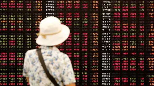 مستثمر ينظر إلى لوحة إلكترونية تعرض مؤشر أسعار الأسهم في شركة وساطة مالية في سيول، كوريا الجنوبية، يوم 1 يوليو 2009