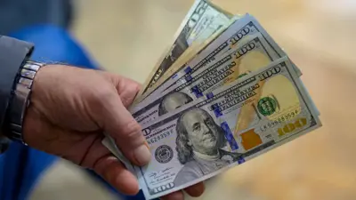 شخص يحمل أوراقاً نقدية من الدولار الأميركي داخل مكتب صرافة في مدينة إسطنبول التركية يوم 28 نوفمبر 2024.