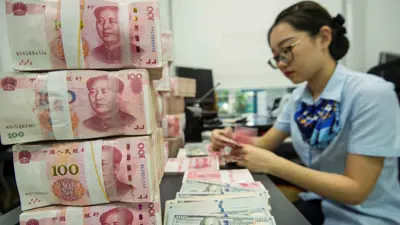 موظفة بنك تعد أوراقاً نقدية فئة 100 يوان وأوراقاً نقدية بالدولار الأميركي بمكتب بنك في نانتونغ بمقاطعة جيانغسو شرقي الصين يوم 28 أغسطس 2019