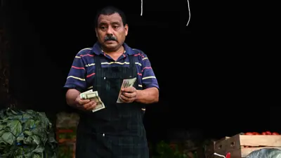 بائع خضروات يعد أوراقاً نقدية من الدولار الأميركي في مدينة السلفادورية يوم 9 يوليو 2024.