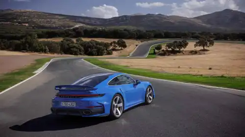 تظهر الصورة سيارة بورشه 911 Turbo S Coupe باللون الأزرق وهي مزودة بتيربو كهربائي