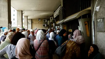 سوريون يصطفون أمام أجهزة الصراف الآلي التابعة للبنك التجاري السوري في دمشق يوم 14مايو 2025