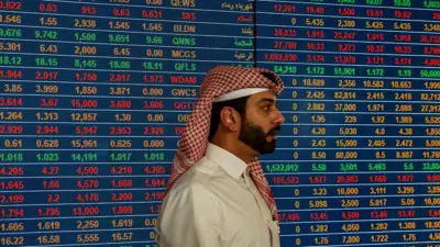 متعامل يمر أمام شاشات بورصة قطر في العاصمة الدوحة يوم 16 يناير 2023