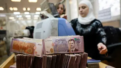 حزم من الأوراق النقدية السورية مكدسة بينما تقوم موظفة بإحصاء الأموال في البنك المركزي السوري في دمشق- 16 ديسمبر 2024.