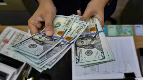 صراف يعد أوراقاً نقدية من الدولار الأميركي في مكتب صرافة في جاكرتا، إندونيسيا، 12 مايو 2026.