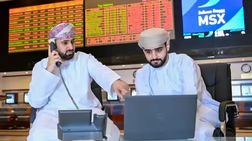 متعاملان يتابعان شاشات تحركات الأسهم في بورصة مسقط، سلطنة عُمان.