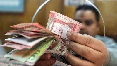 موظف في أحد البنوك المصرية يعد أوراقاً نقدية بما فيها الريال السعودي.