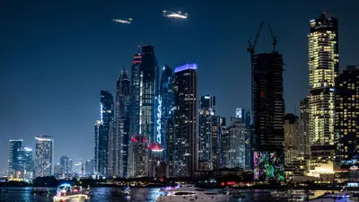 قوارب تبحر قبالة جزيرة بلوواترز خلال عرض للقفز بالمظلات قرب مرسى مدينة دبي، الإمارات العربية المتحدة، يوم 13 ديسمبر 2024
