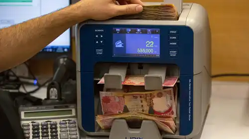 وكيل صرافة يقوم بعدّ أوراق نقدية من الدينار العراقي في شركته بمدينة البصرة، جنوبي العراق - 12 ديسمبر 2023.