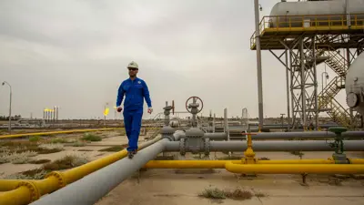   شخص يسير على أنبوب في حقل نهر بن عمر للغاز الطبيعي، جنوب العراق يوم 21 أبريل 2020