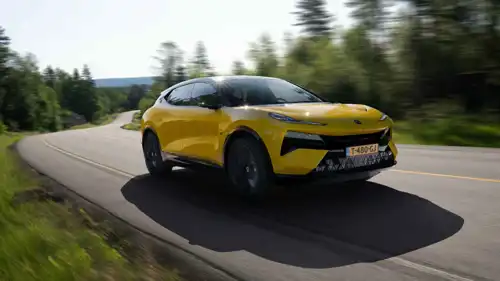 سيارة Lotus Eletre تنطلق بسرعة على طريق ريفي متعرج، مظهرة تصميمها الرياضي الجريء وهيكلها الانسيابي