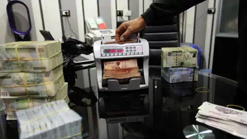 موظف في مكتب صرافة يستخدم آلة عدّ النقود لفرز أوراق الدينار الليبي في طرابلس، 27 أبريل 2016.